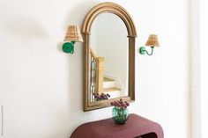 Entryway with gilded mirror, sconces, flowers, and suitcases