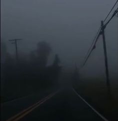 a foggy road with power lines and telephone poles