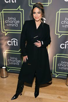 a woman standing on top of a wooden floor next to a black sign with words above her