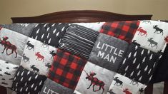 a baby bed with a quilted moose theme on it's cover and the words little man written in white letters