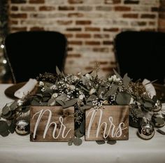 two wooden signs that say mr and mrs sitting on top of a white table cloth