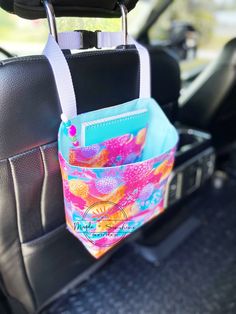 a colorful bag hanging from the back seat of a car with it's pocket open