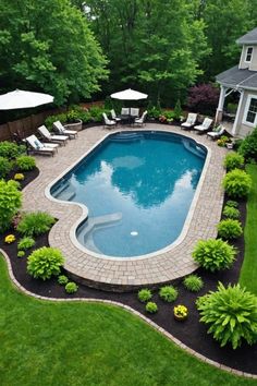 an above ground swimming pool surrounded by lush green grass and trees with white umbrellas