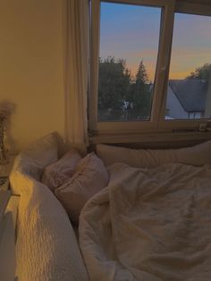 an unmade bed sitting in front of a window with the sun shining through it