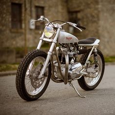 the motorcycle is parked on the side of the road in front of an old building