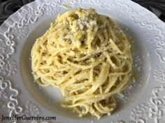 a white plate topped with pasta covered in sauce and parmesan cheese on top