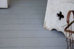 the corner of a porch with an iron planter next to it and a white painted wall