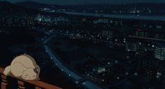 a cat sleeping on top of a wooden fence next to a night cityscape