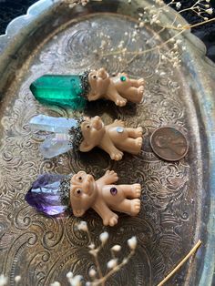 three small plastic animals sitting on top of a metal tray next to a dime coin