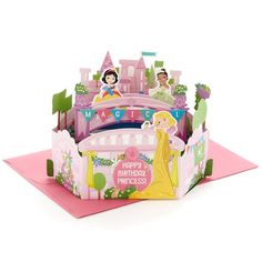 a birthday card with princesses and castle on the front, sitting on top of a pink envelope