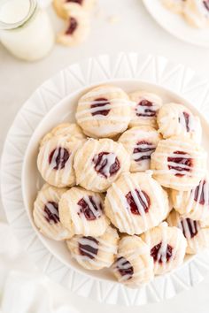 a white plate topped with cookies covered in icing next to a glass of milk