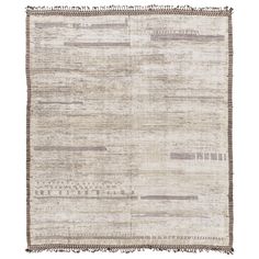 an old rug with fringes on the edges and stripes in grey, beige and white