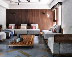 a living room filled with lots of furniture next to a wooden wall and ceiling fan