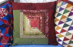 two colorful pillows sitting next to each other on a blue couch with red and green quilts