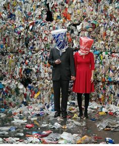 a man and woman standing next to each other in front of a pile of trash