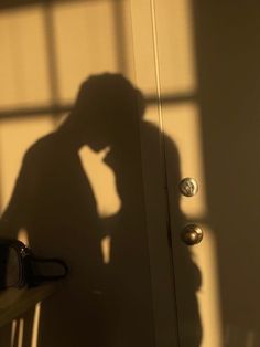 the shadow of a man standing in front of a door with his hand on his head