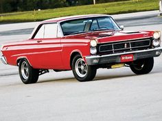 an old red car is parked in a parking lot