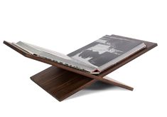 an open book sitting on top of a wooden stand with a magazine in the middle