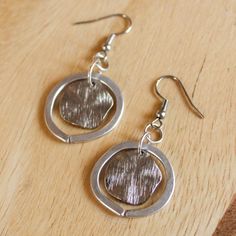 These beautiful silver earrings are handmade with aluminum wire and a dime-sized textured metal center. Perfect for daily wear, special occasions, or as a gift! Please note that these earrings are handmade to order and because of their one-of-a-kind nature may vary from the exact pair shown in the photos. The earrings are sisters, not twins, so both earrings in a set may vary slightly from each other! Nickel-free Pewter Silver Earrings, Cadmium-free Metal Earrings For Everyday Wear, Silver Pewter Earrings As Gift, Silver Pewter Earrings For Gift, Cadmium-free Silver Hoop Earrings, Silver Metal Earrings For Everyday, Cadmium-free Silver Earrings For Everyday Wear, Hammered Metal Earrings Gift, Hammered Metal Earrings As Gift