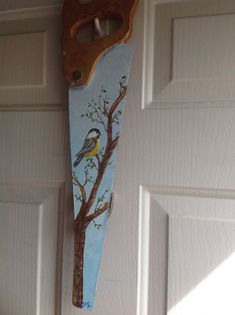 a painting of a bird perched on a tree branch hanging from a garage door with a pair of scissors