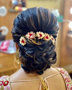 the back of a woman's head with flowers in her hair and gold jewelry