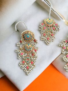 This multani work thapa kundan tikka and jhumka earrings set is gorgeous and very versatile to wear. The gold plating is traditional and the colors will match with any type of outfit. Kundan Necklace With Latkans, Kundan Danglers With Zari Work In Temple Jewelry Style, Gold Plated Chandbali Kundan Necklace In Temple Style, Temple Jewelry Kundan Danglers With Zari Work, Temple Jewelry Style Bridal Earrings With Zari Work, Gold Plated Chandbali Jewelry Sets, Kundan Meenakari Earrings In Temple Jewelry Style, Gold Plated Meenakari Jhumkas Temple Jewelry, Gold Plated Chandbali Traditional Jhumkas