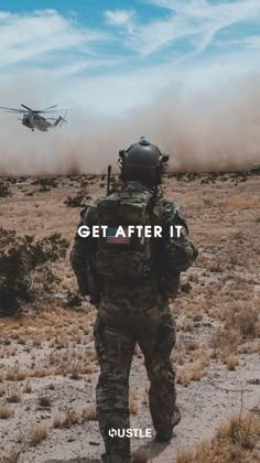 a man in camouflage is looking at a helicopter that is flying over him with the words get after it