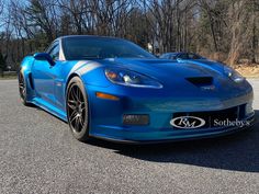 the blue sports car is parked on the side of the road in front of some trees