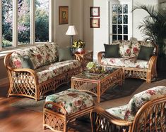 a living room with wicker furniture and large windows overlooking the trees in the background