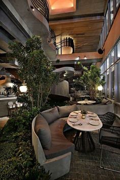 the interior of a restaurant with tables, chairs and plants on the wall above it