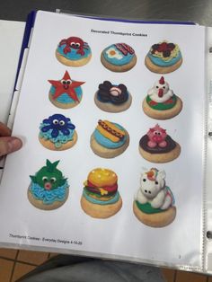 an open book with twelve decorated cookies on it's front cover, in the shape of cartoon characters