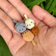 three small crocheted animals sitting in the palm of someone's hand