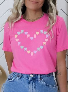 ✦ St. Patrick's Day version of this shirt: https://www.etsy.com/listing/1390930938/ Get ready to be OBSESSED with this cute tooth and candy heart Valentine shirt. Buy today for yourself or for someone special.  Q U I C K F A C T S  ✦ Unisex Bella+Canvas 3001 available in: black, charity pink, maroon, heather raspberry, and red ✦ Light fabric ✦ Retail fit/ runs true to size ✦ Printed and shipped from the USA with love  S I Z I N G  ✦ Runs true to size ✦ Solid colors are 100% cotton except Ash - 9 Pink Short Sleeve Shirt With Heart Graphic, Pink Crew Neck Shirt For Valentine's Day, Cute Shirt With Heart Graphic And Crew Neck, Cute Crew Neck Shirt With Heart Graphic, Valentines Dental, Tooth Shirt, Dental Shirt, Dental Shirts, Cute Tooth