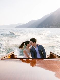 a man and woman kissing on the back of a boat