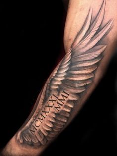 a man's arm with an angel wing tattoo on it