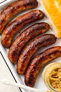 several sausages on a plate with mustard and bread