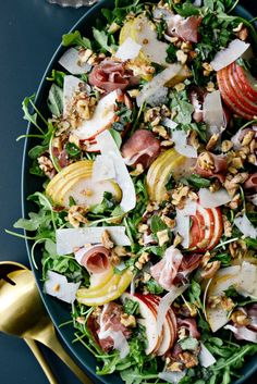 a salad with apples, nuts and greens in a blue bowl on top of a table