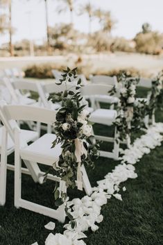 an outdoor ceremony set up with white chairs and flowers