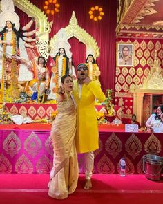 a man and woman pose for a photo in front of an elaborately decorated stage