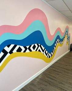 an office wall painted with colorful lines and waves on it's side, along with wood flooring