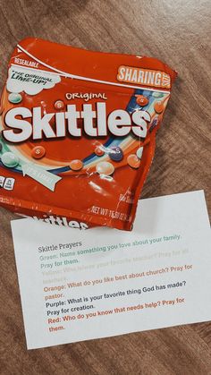 a package of skittles sitting on top of a table next to a piece of paper