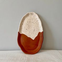 a brown and white plate sitting on top of a table next to a gray wall