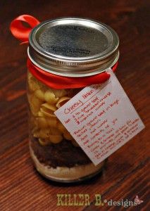 a jar filled with lots of food on top of a wooden table next to a red ribbon