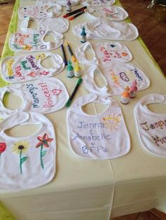 baby bibs are laid out on a table with crayons and paintbrushes