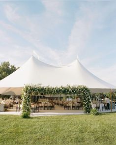 a large tent with tables and chairs set up for an outdoor wedding reception in the grass