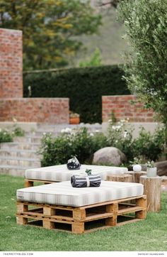 a couch made out of wooden pallets sitting in the middle of a lawn area