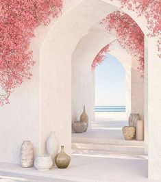 an archway with pink flowers and vases next to it