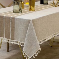 a table with two vases sitting on top of it next to a white table cloth