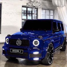 a blue suv is parked in front of a white brick wall and chandelier