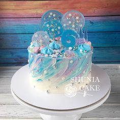 a blue and white cake sitting on top of a table next to a wooden wall